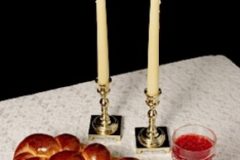 Challah, candlesticks, wine on white tablecloth