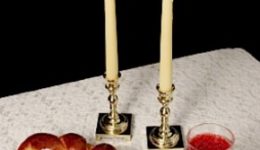 Challah, candlesticks, wine on white tablecloth