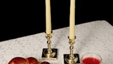 Challah, candlesticks, wine on white tablecloth