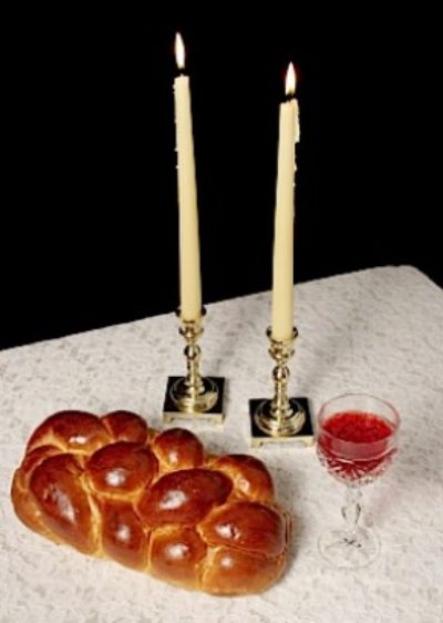 Challah, candlesticks, wine on white tablecloth
