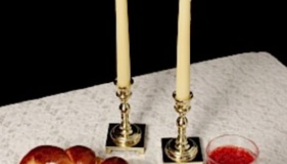 Challah, candlesticks, wine on white tablecloth